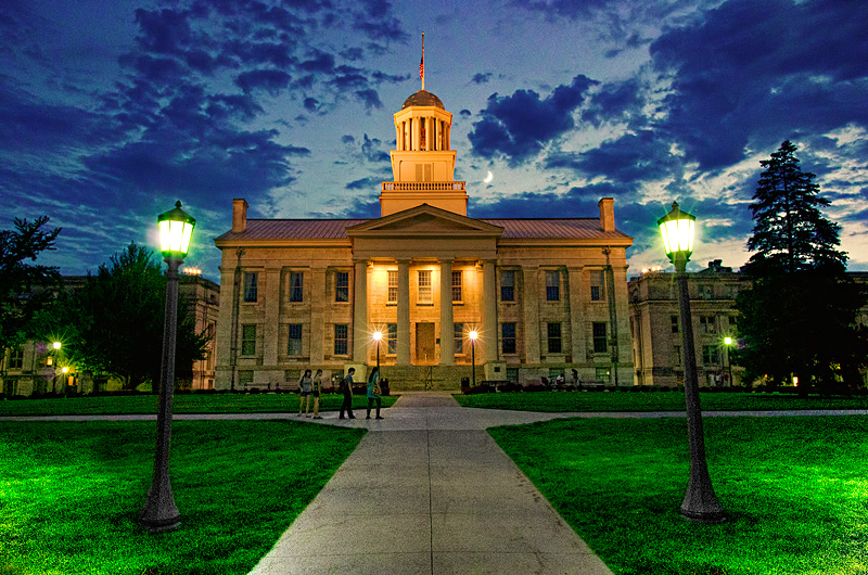 campus building with a lawn with sidewalks and a cloudy sky at night