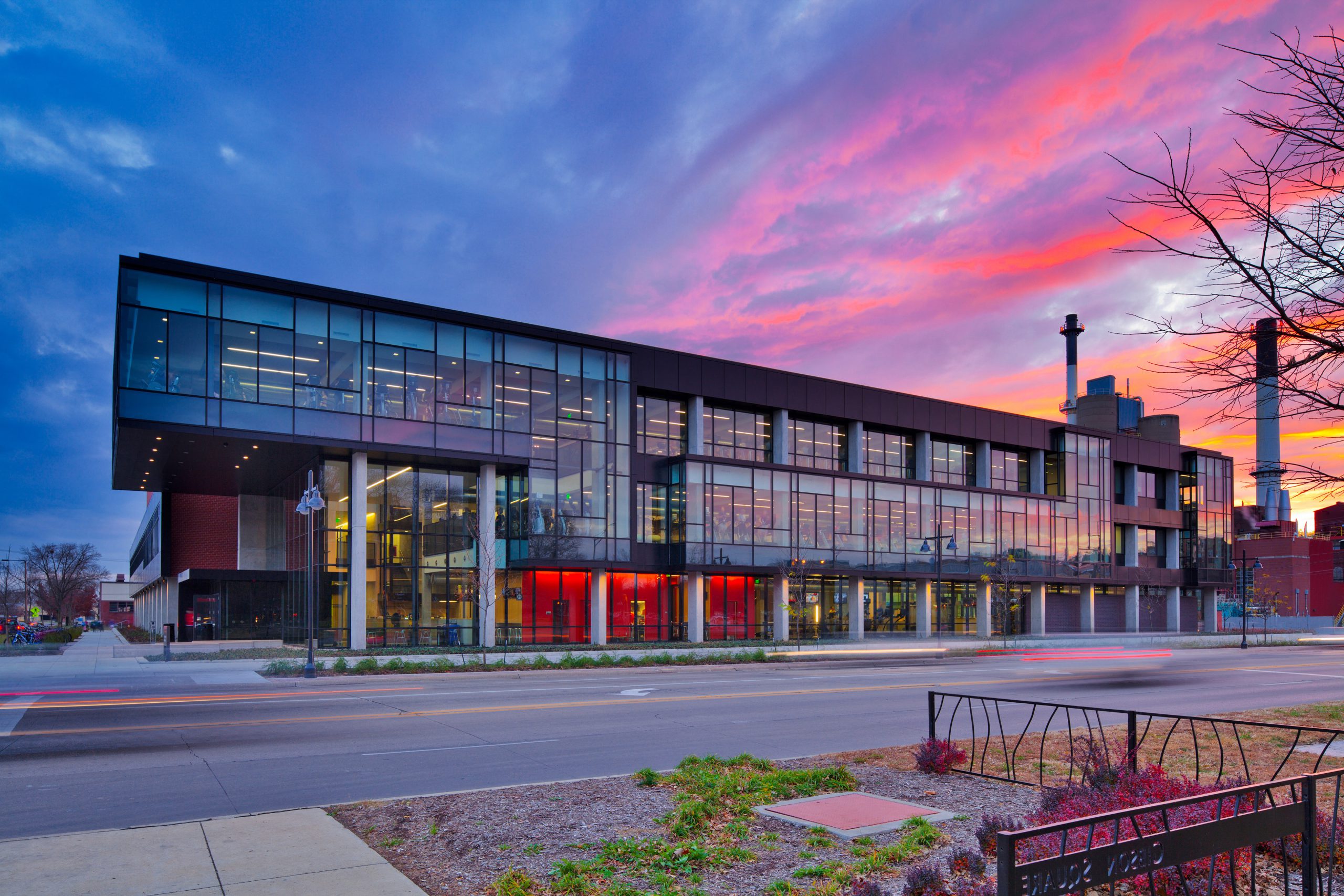 street view of a campus glass building with a sunset in the sky